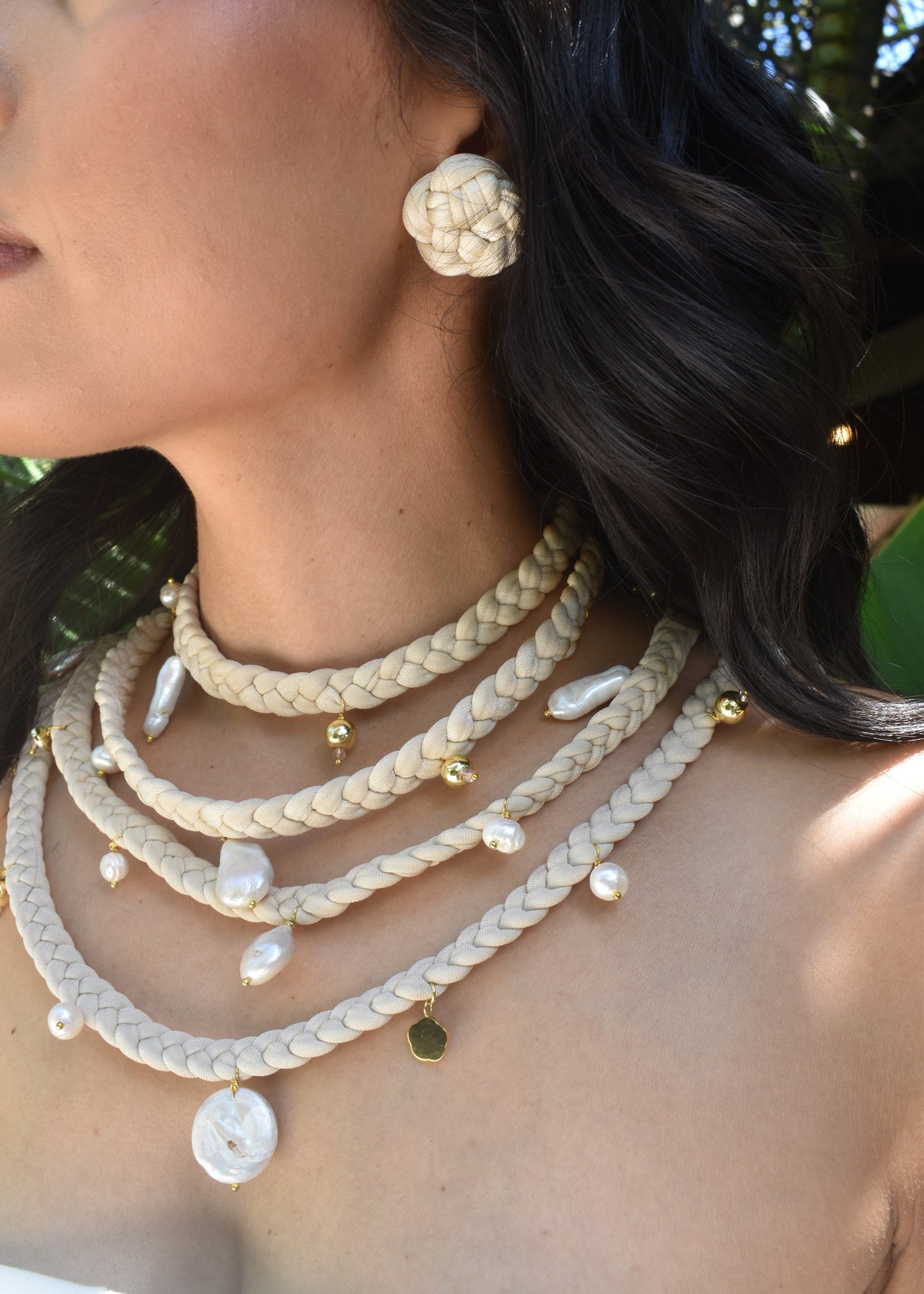 Close-up of a person wearing multiple beaded necklaces with a blurred background