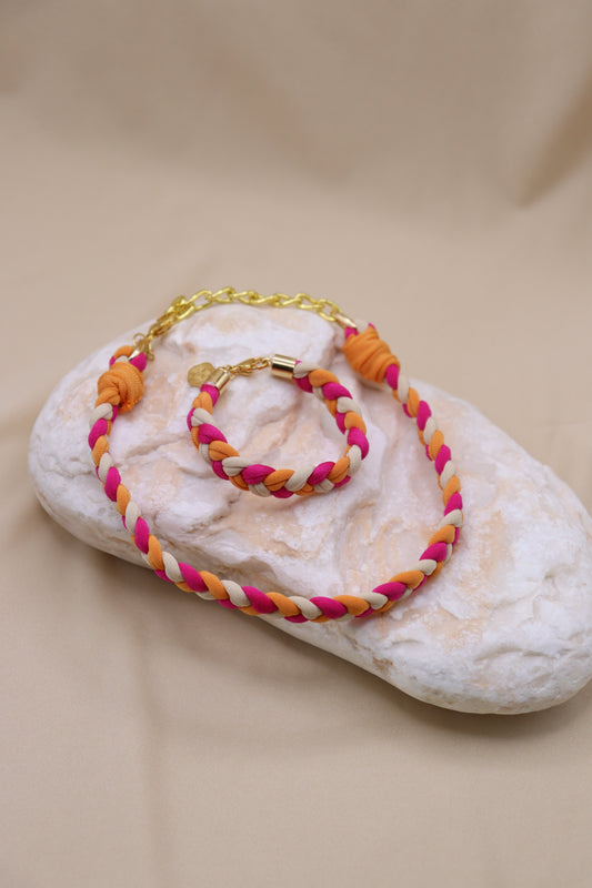 Colorful braided necklace and bracelet set on a textured beige surface