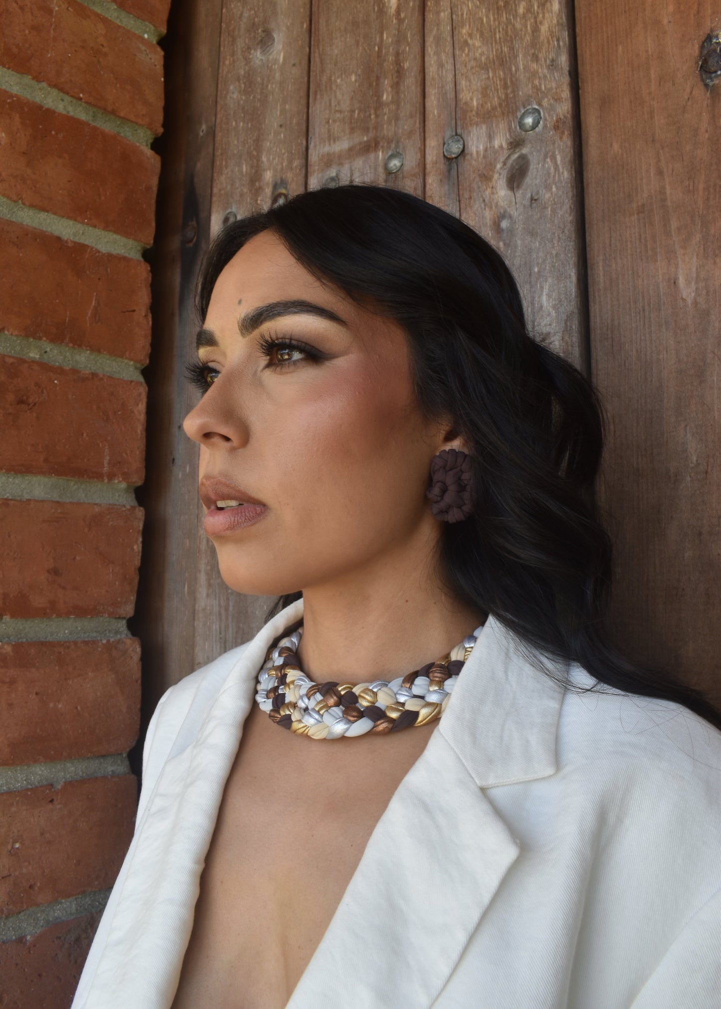 Model wearing Catalina handcrafted statement necklaces in neutral tones with brown earrings from the Radices Collection, styled with a white blazer, elegant artisanal jewelry by Majaca.